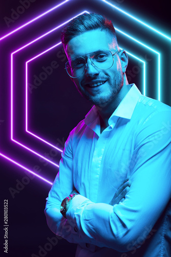 Young handsome model posing in a studio in a trendy neon light. Fashionable man in a stylish suit. Vibrant color. Bright colorful light effects. Disco style. Overlay. Gel filter. Supersaturated