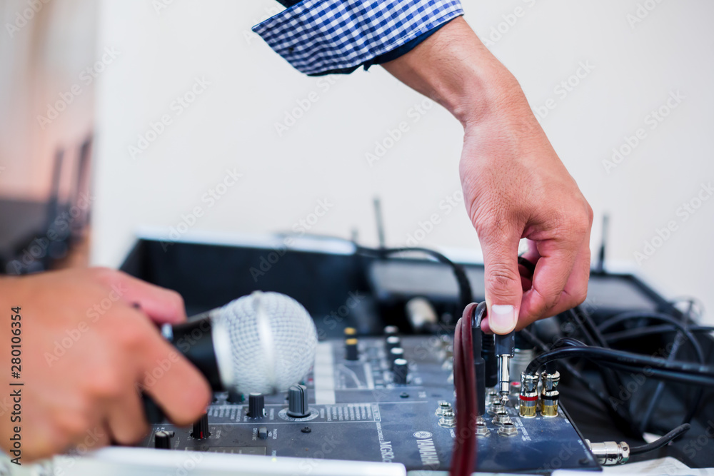 Microphone in hand and plugin audio jack to mixer controller in the control room, Sound mixer control for live music and studio equipment, music equipment concept. Microphone in hand and plugin audio jack to mixer controller in the control room, Sound mixer control for live music and studio equipment, music equipment concept.