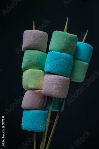Multicolored marshmallow on a stick on a gray background