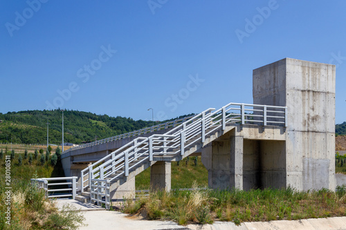 Concrete pedestrian overpass bridge in rural area on isolated green and blue background