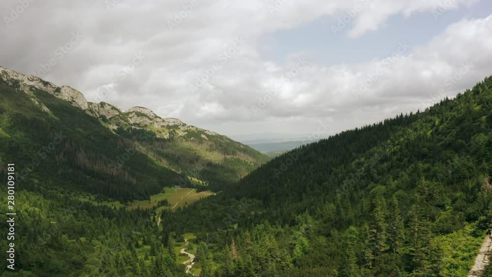 Epic aerial flight over a mountain valley in the Canadian mountains. Moving forward to the pine forest, forest and mountain valley with a solar flare on a summer day. Drone Shot 4K. Epic aerial flight over a mountain valley in the Canadian mountains. Moving forward to the pine forest, forest and mountain valley with a solar flare on a summer day. Drone Shot 4K.