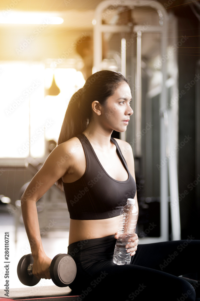 Fototapeta premium Attractive girl ASEAN citizenship Relax, drink water after exercising in the gym. Concept exercise and health care