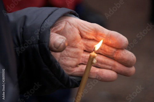Single flaming candle in old female hands