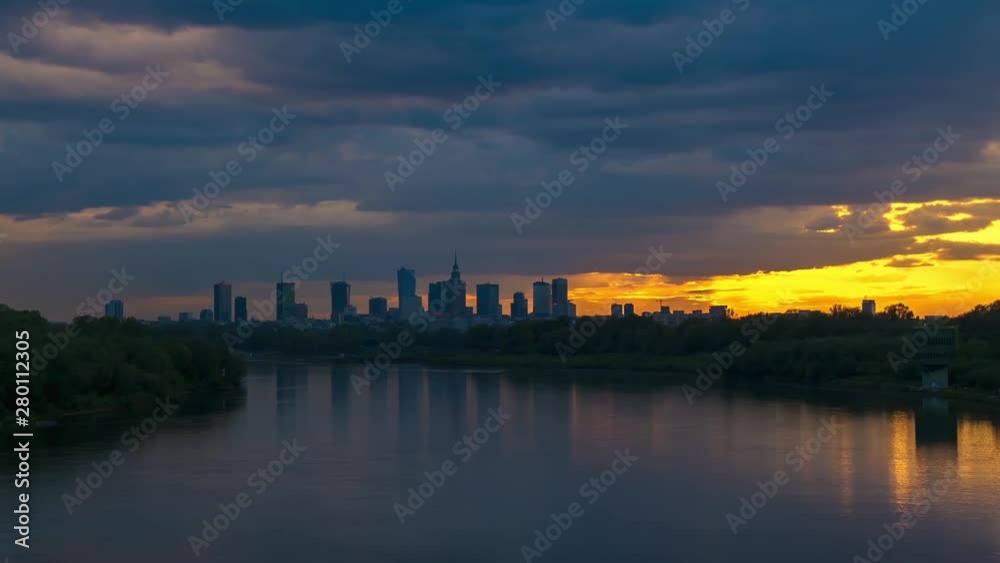 View on Cityscape of Warsaw City Skyscrapers Buildings on Horizon and Vistula or Wisla River with cloudy sky at Summer Evening Sunset. Time lapse. Poland View on Cityscape of Warsaw City Skyscrapers Buildings on Horizon and Vistula or Wisla River with cloudy sky at Summer Evening Sunset. Time lapse. Poland