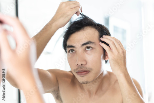 Close up man looking reflection in the mirror serious hair loss problem for health care shampoo and beauty product concept