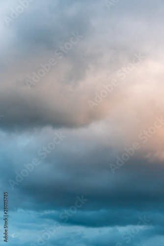 Stormy sky at twilight with clouds in various shades of blue, gray, and orange 
