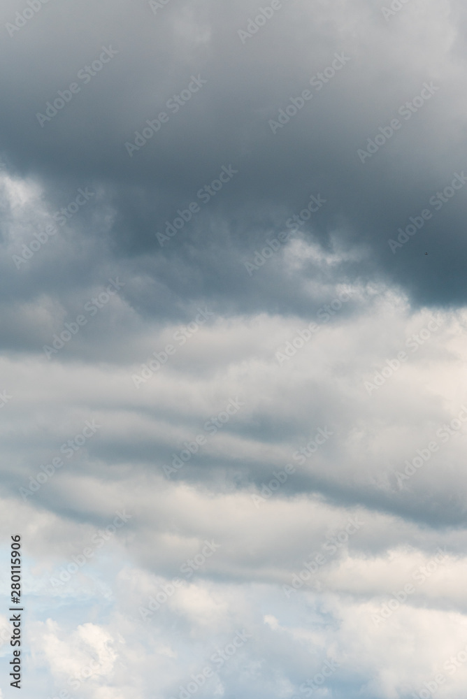 Stormy sky with clouds in various shades of grey with a hint of blue sky