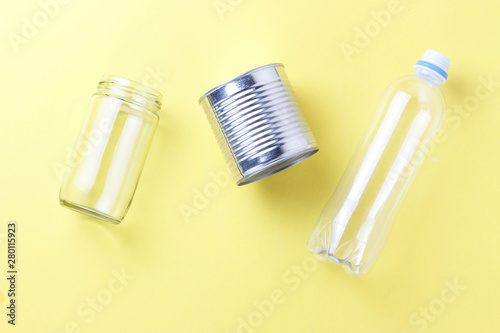 Glass jar and plastic bottle  iron garbage on yellow background  top view.