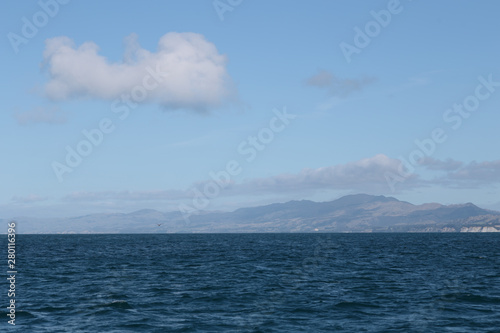 Delightful sea landscape with blue surface of the water, magic feather clouds on the sky over mountain in Kaikoura,New Zealand