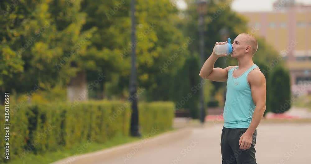 Handsome man drinks water from a bottle after a workout. Athlete finished the exercises. Handsome man drinks water from a bottle after a workout. Athlete finished the exercises.