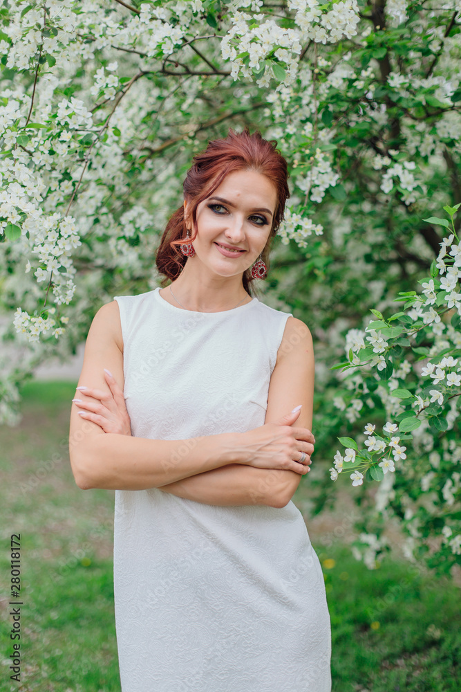 Charming woman wearing beautiful white dress under the apple tree Charming woman wearing beautiful white dress under the apple tree