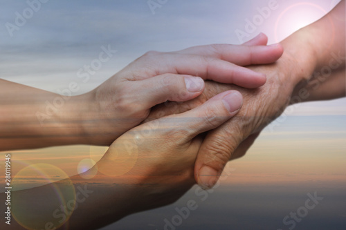 Caregiver, carer hand holding elder hand in hospice care with sky sunset background. Euthanasia  Philanthropy kindness to disabled concept. photo