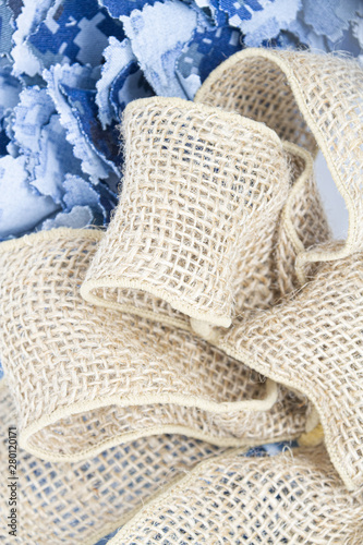 Strands of fabric from a Navy aquaflauge uniform on a white background with a burlap bow.