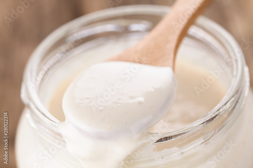 Fresh homemade bubbly sourdough starter, a fermented mixture of water and flour to use as leaven for bread baking, on wooden spoon (Selective Focus one third into the spoon)