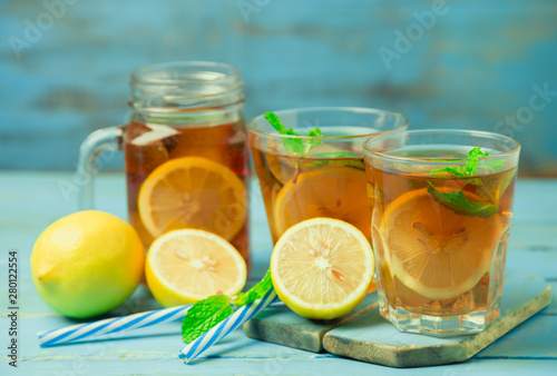 Iced tea with lemon slices and mint on wood background