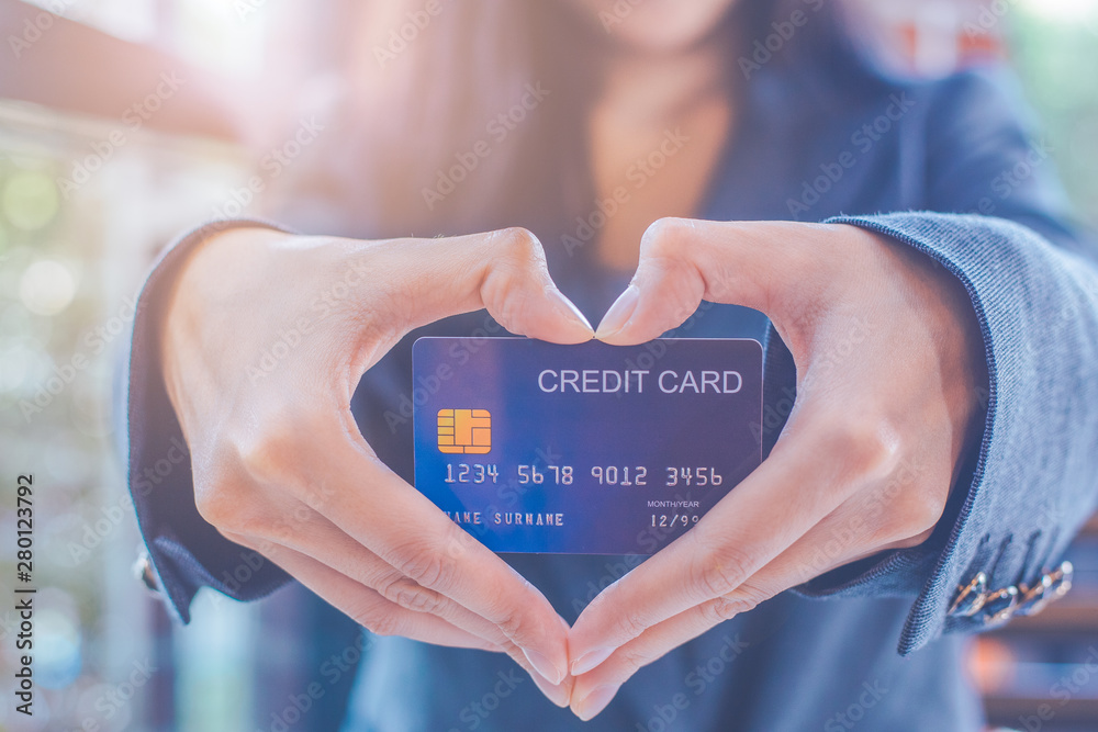 Female businessmen are holding a credit card and making a heart-shaped hand.