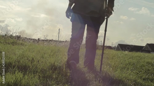 Woman walks in countryside with a walking stick
