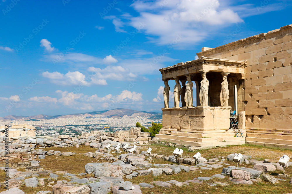 Fototapeta premium Ruins of famous ancient greek temple Erechtheion, on the north side of the sacred rock of the Acropolis of Athens with statues of Caryatids under blue sky with clouds