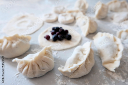 Sculpted dumplings with Irga, raw dough. Stages of preparation of sweet flour boiled dishes. White table with flour and roll the dough.