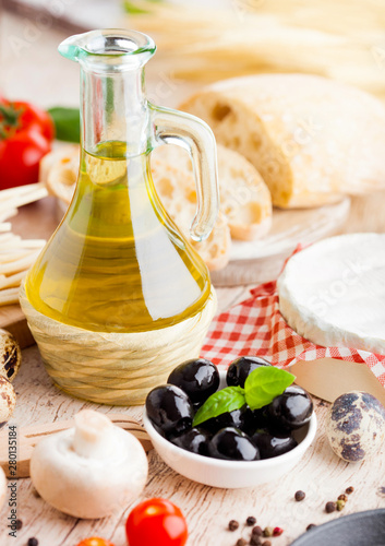 Homemade spaghetti pasta with quail eggs with botle of olive oil and cheese on wooden background. Classic italian village food. Garlic, black and green olives, oil and bread. Basil leaf