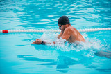 Closeup male athlete swimming breaststroke in pool during Champions.