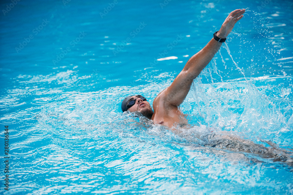 Athletic Young man swimming on Backstroke style. Swimming competition.