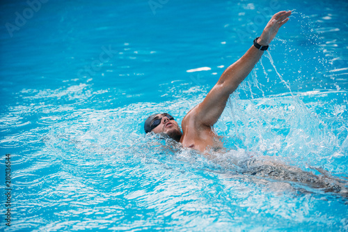 Athletic Young man swimming on Backstroke style. Swimming competition. © ManuPadilla