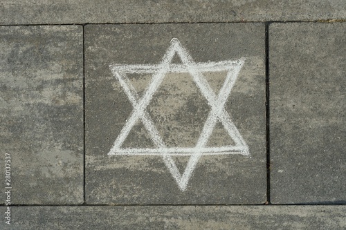 Abstract image of six pointed star, written on grey sidewalk