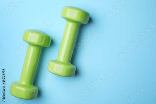 Bright dumbbells and space for text on color background, flat lay. Home fitness