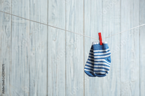 Pair of socks on laundry line against wooden background, space for text. Baby accessories