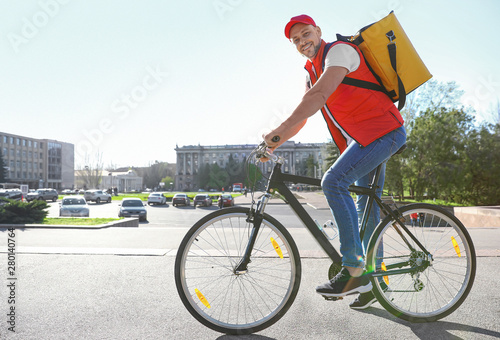 Fototapeta Naklejka Na Ścianę i Meble -  Male courier on bicycle delivering food in city