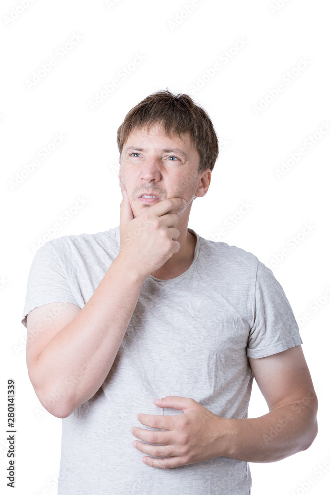 A young casual man in a t-shirt thoughtfully holds his hand to his chin. Сoncept photo of a thinking man. A young casual man in a t-shirt thoughtfully holds his hand to his chin. Сoncept photo of a thinking man.