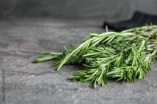 Bunch of fresh rosemary on grey table, space for text