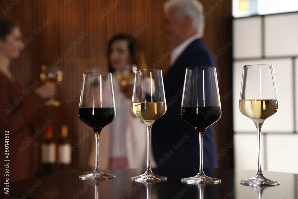 Glasses of different wines on table against blurred background