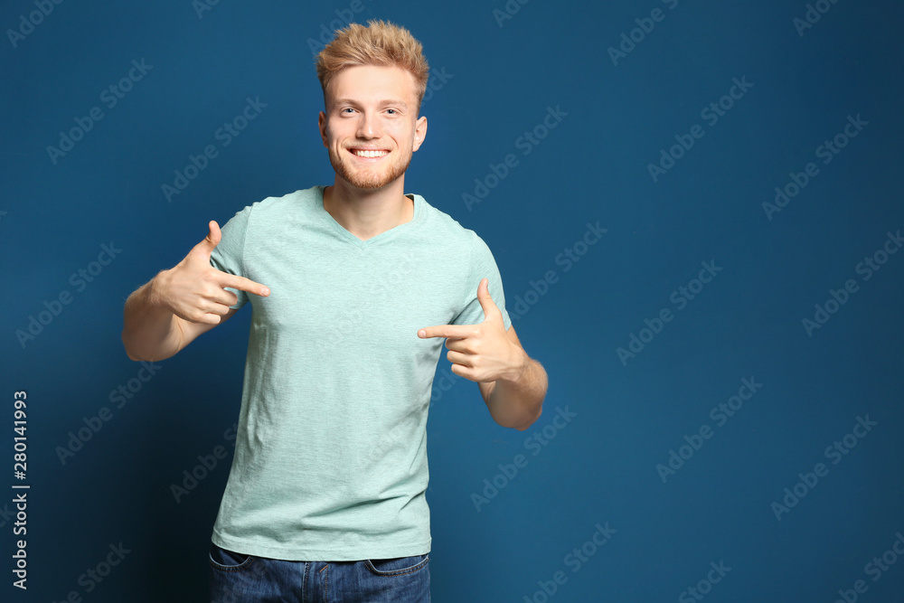 Naklejka premium Young man wearing blank t-shirt on blue background. Mockup for design