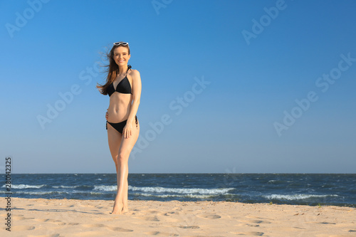 Beautiful woman in bikini on sea coast. Space for text