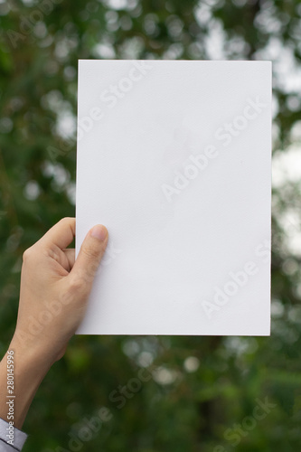 Woman holding paper blank of drawing paper paper with natural background.