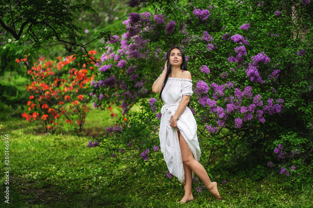 photo of young woman walking through lilac garden in bloom.Outdoor . Barefoot. photo of young woman walking through lilac garden in bloom.Outdoor . Barefoot.