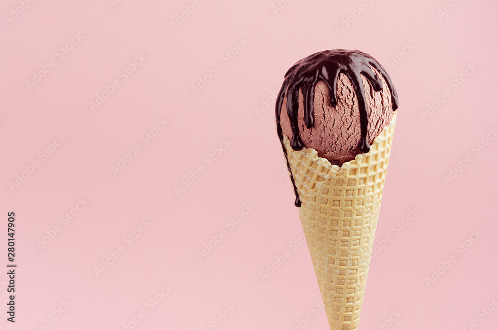 Brown ice cream in waffle cone with chocolate sauce on soft light pastel pink background, closeup, half, details, top.