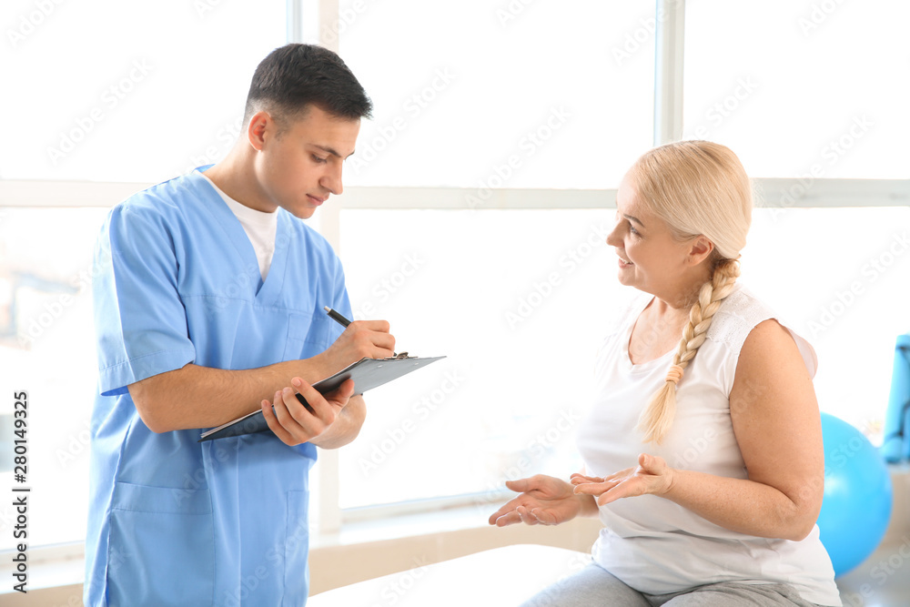 Fototapeta premium Physiotherapist working with mature patient in rehabilitation center