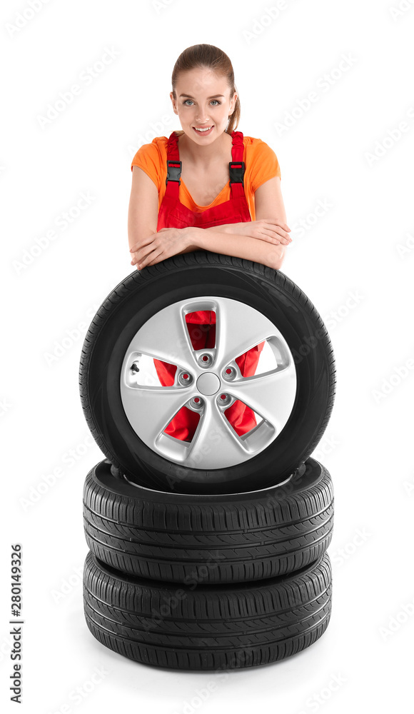 Young female mechanic in uniform with car tires on white background Young female mechanic in uniform with car tires on white background
