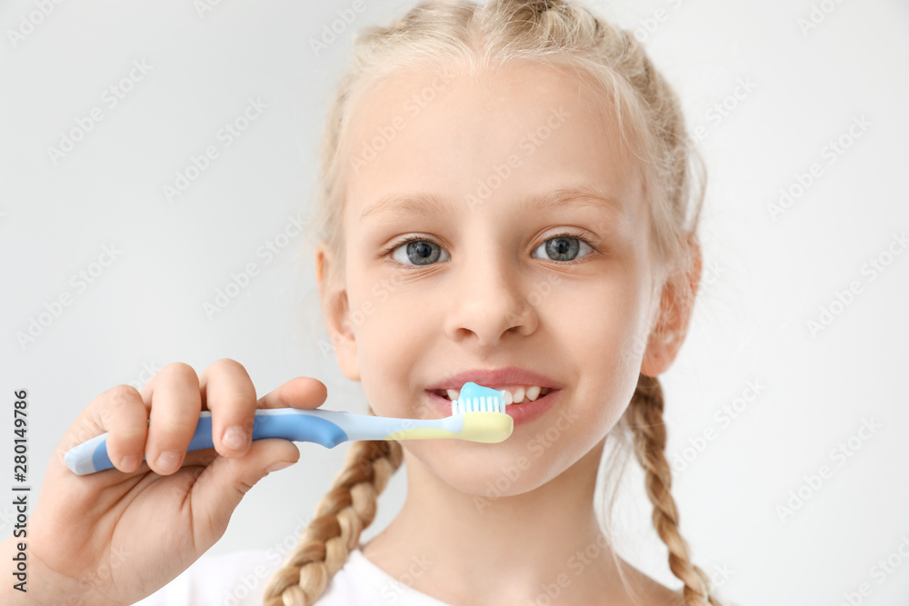 Little girl cleaning teeth on light background Little girl cleaning teeth on light background