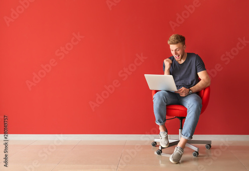 Happy young man with laptop...