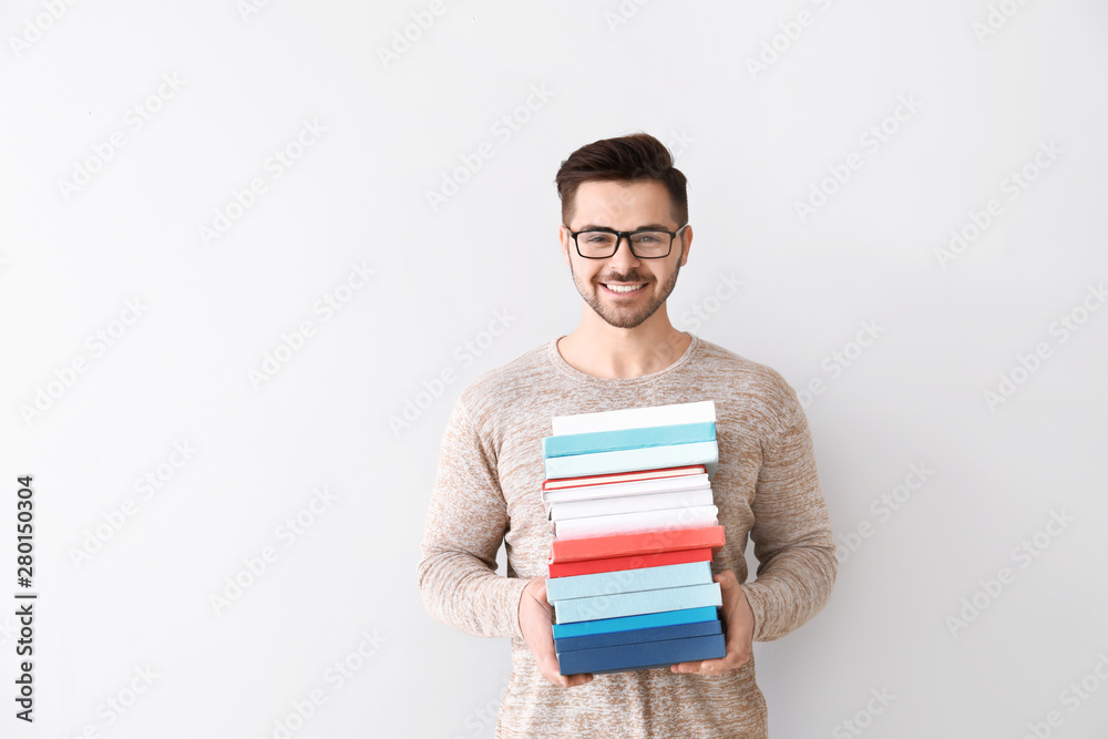 Handsome young man with books on light background Handsome young man with books on light background