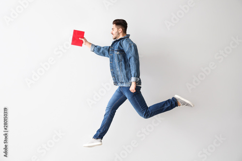 Jumping young man with book...