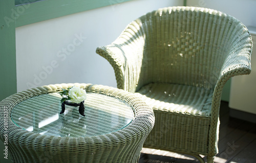 A table and the chair made of the rattans of the room and the flower which was displayed photo