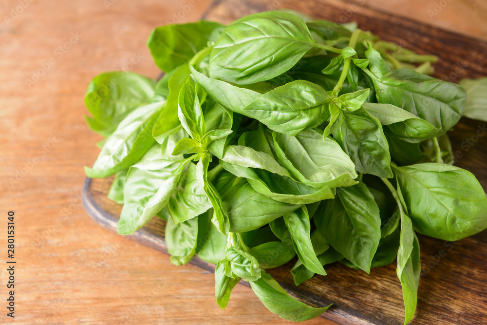 Cutting board with fresh green basil on wooden table Cutting board with fresh green basil on wooden table