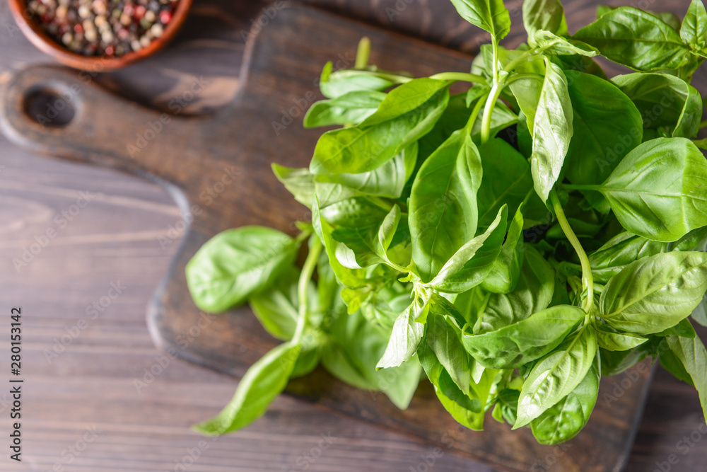 Board with fresh green basil on wooden table, top view Board with fresh green basil on wooden table, top view