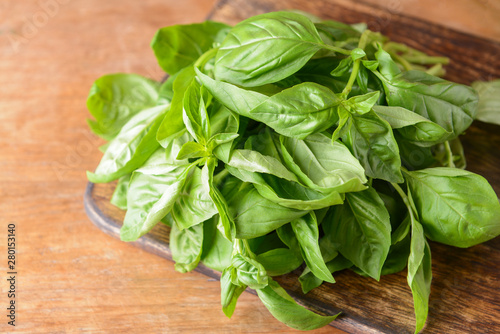 Cutting board with fresh green basil on wooden table