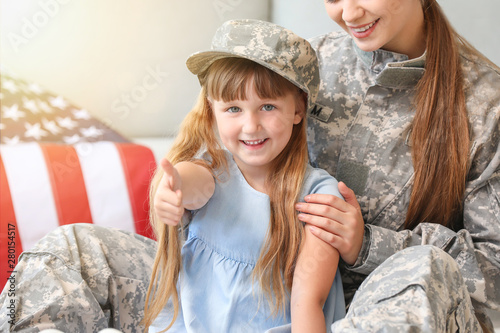 Happy female soldier with her daughter at home